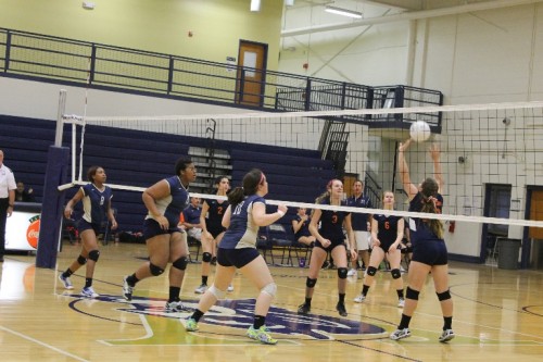 The Lady Blue Devils  rush the net as they ready for a spike from Lee-Davis.